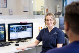 A woman in scrubs talks to a colleague in a hospital setting