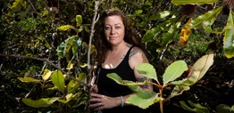 Woman with arm tattoos in a bush setting