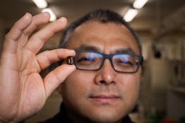 A man holding a coffee bean in front of the camera