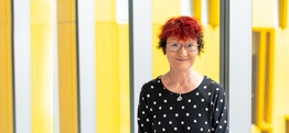 A woman looking at the camera against a modern yellow and glass background