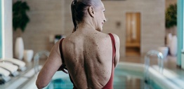 Back view of an elderly woman in maroon swimwear