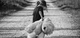 Girl holding plush toy on a dirt road