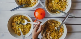 Close-up of a person getting noodles from four different bowls