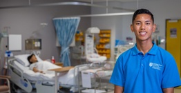 Student in nursing lab with sim doll in hospital bed