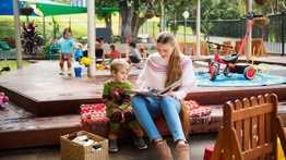Early Childhood teacher reading with pupil in playground