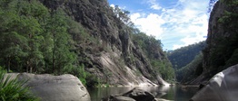 A steep valley with large boulders and a river running through it