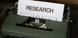 The words research in capital letters on a pieced of paper sitting in a typewriter