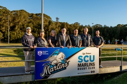 A group of people standing in front of a banner with the words SCU Marlins