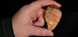 Close up of a hand holding stone tools