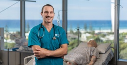 Student in blue polo with stethoscope with sim doll in background