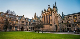Exterior of a sandstone university with a grass lawn