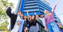 Group of students posing in front of blue building