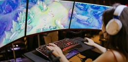 Woman in front of a computer screen playing esports League of Legends