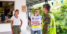 Two women and a man talking in front of a temporary emergency canteen