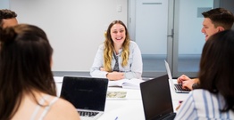 Student smiling in group with laptops