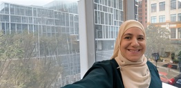 Woman standing in front of a glass window smiling