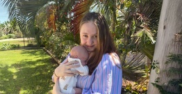 Brittany Elliott faces camera cuddling her baby