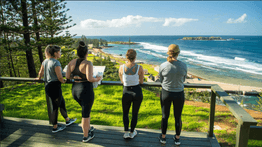 Three people in leggings gazing out to sea