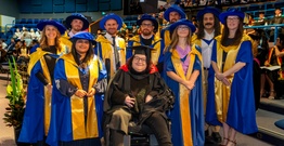 Graduates in robs and caps at graduation ceremony smiling
