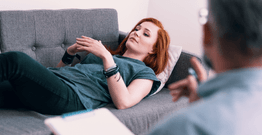 Lady lying on a couch talking to a therapist