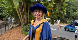 Student in academic robes smiling at camera