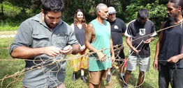 Indigenous men making a net using plant fibres