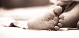 Monochrome close-up of a newborn's delicate foot on a soft surface