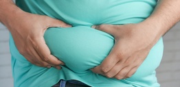 An overweight man holding excess skin in his belly