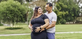 A pregnant woman being hugged by a man