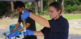 A woman wearing gloves and using scientific instruments in the field