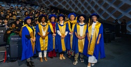 Men and women in graduation robes smiling at camera