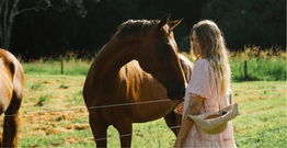 A woman, Scarlett Austin, stands beside a horse