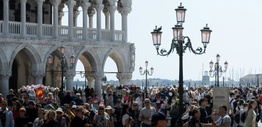 A bustling city square filled with people overlooking a waterway