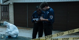 American police looking at clipboard in front of police tape