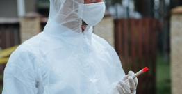 Person is PPE holding sample in tube