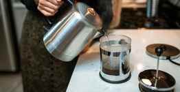 Boiling water poured from kettle into coffee plunger