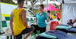 Health student working with athlete, both lifting one leg