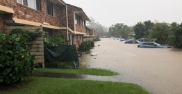 A flooded street with unit blocks and cars underwater