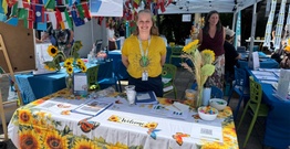 Woman standing at market stall with sunflowers