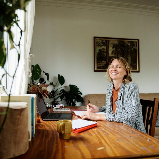Woman smling at camera while writing in a book