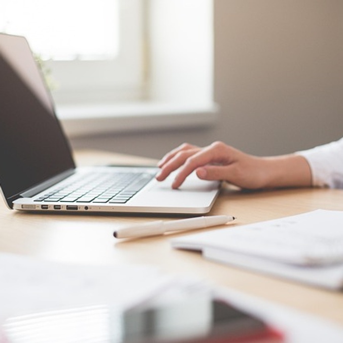 person typing on laptop keyboard with one hand