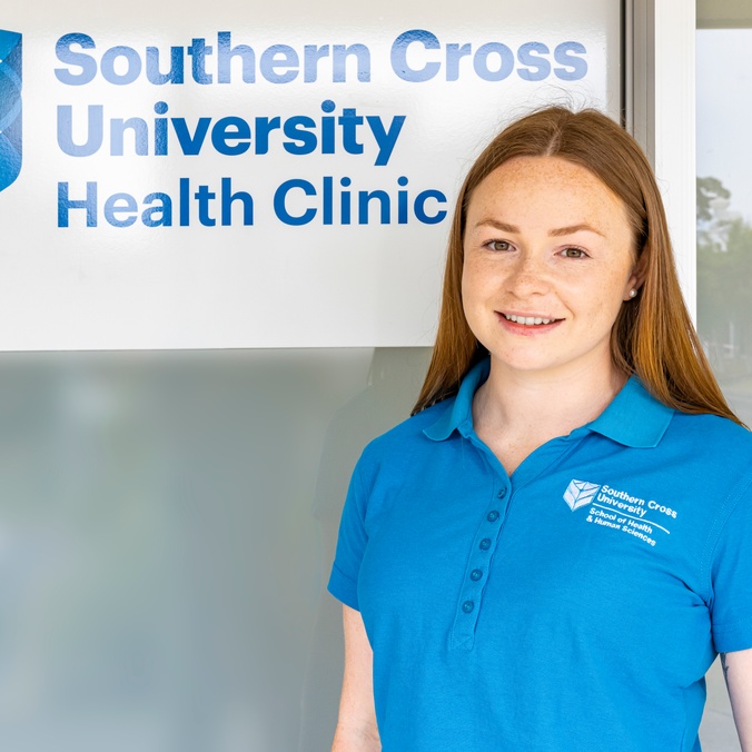 Student in blue polo standing in front of health clinic