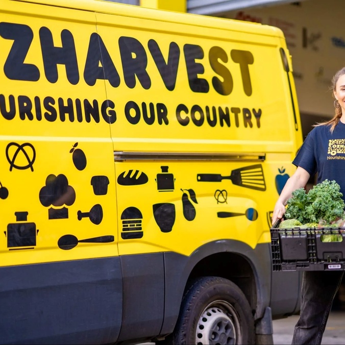 OzHarvest food volunteer stands beside a yellow delivery truck