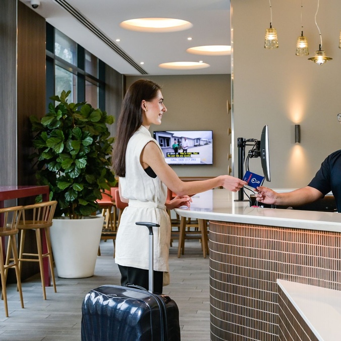 Alumnus Cindy Van Der Wal stands at a hotel reception desk