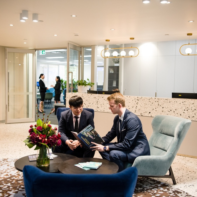 Two male Tourism and Hotel Management students sit in the foyer of The Hotel School - Melbourne.