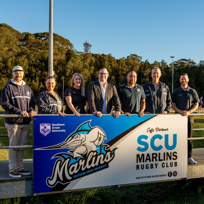 A group of people standing in front of a banner with the words SCU Marlins