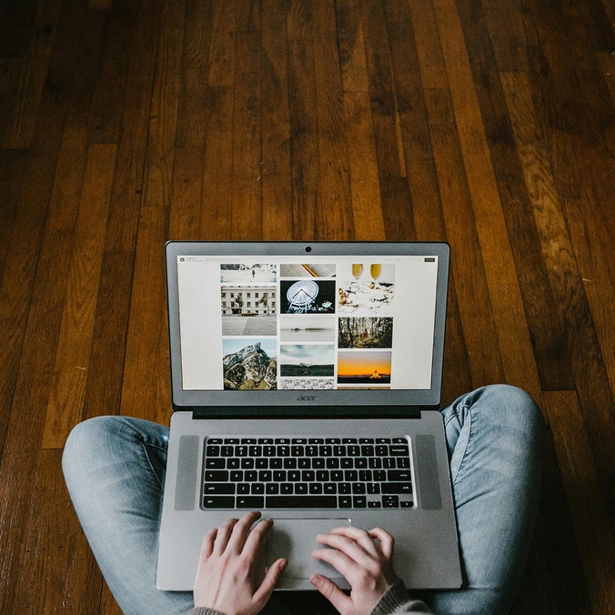 student sitting on ground typing on laptop