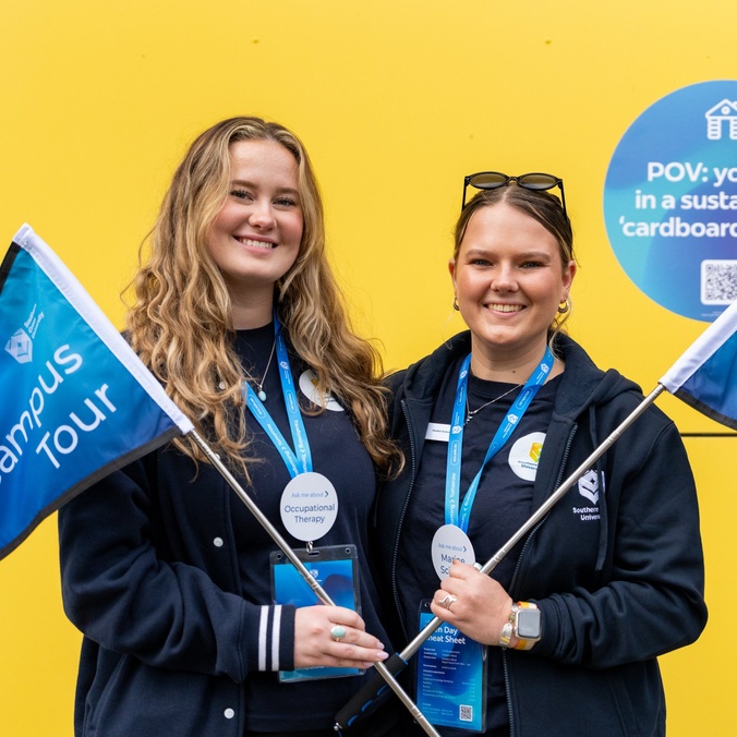 Two female students holding campus rous flags