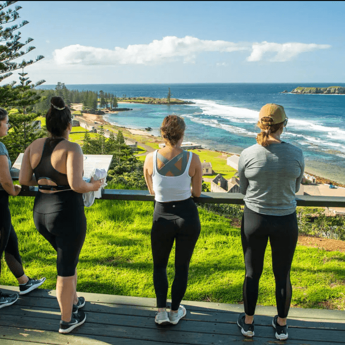 Three people in leggings gazing out to sea