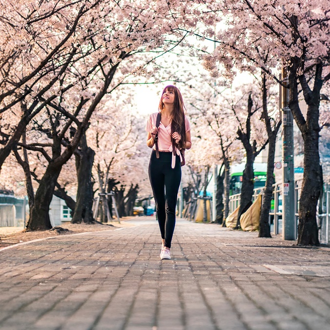 Girl walking through blossom-filled walkway in Japan
